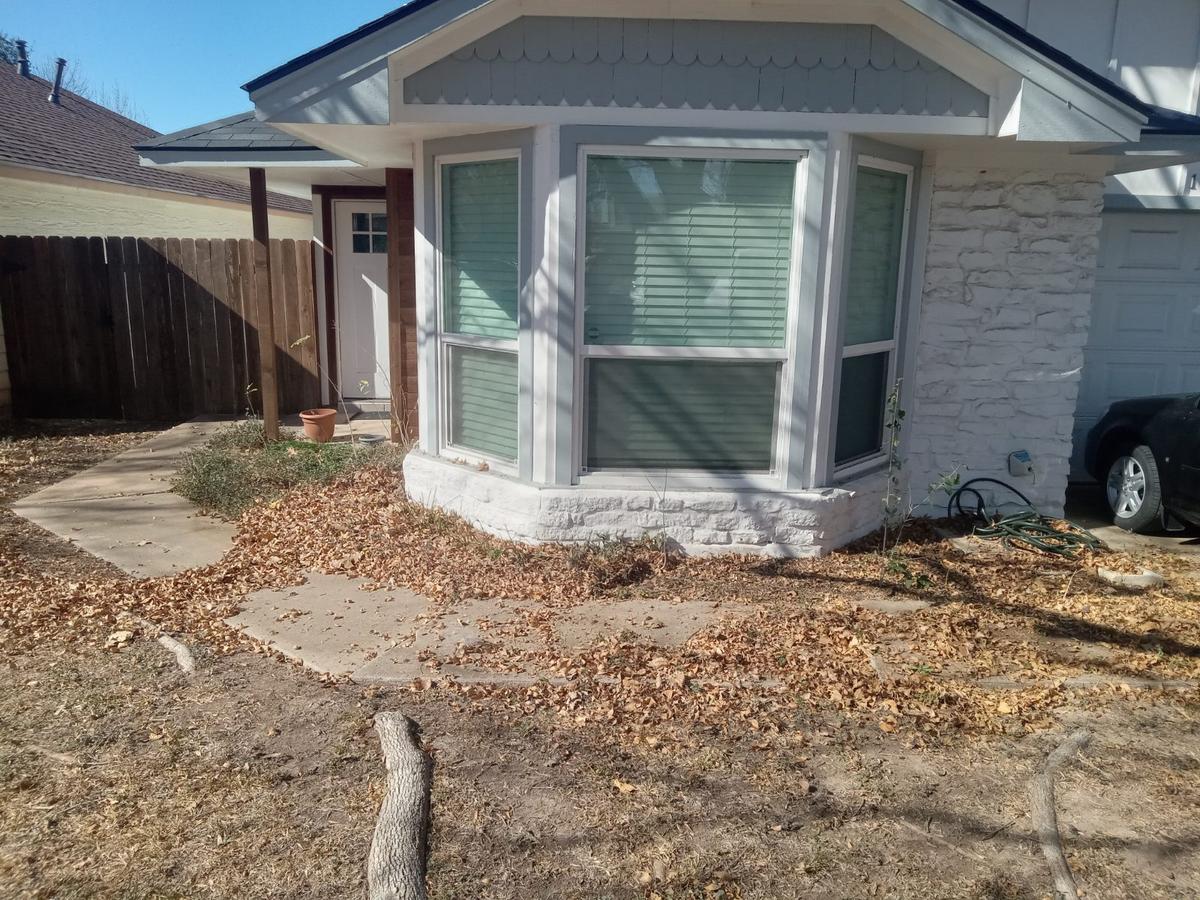 Leaf-covered front bed before a seasonal cleanup