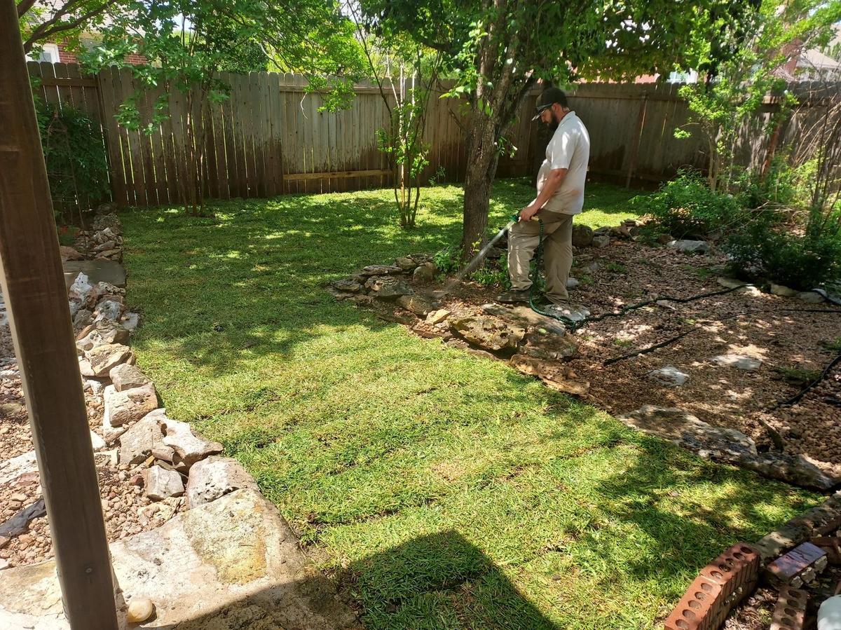 Eco Lawn Pros team member trimming along a backyard bed